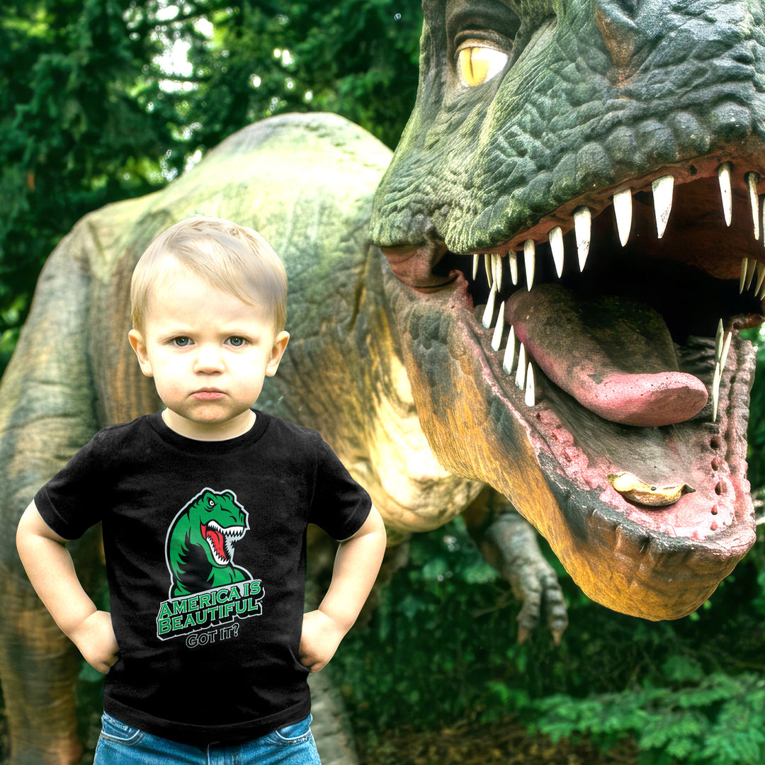 Child wearing a black t-shirt with a T-rex dinosaur graphic in front of a large dinosaur statue.