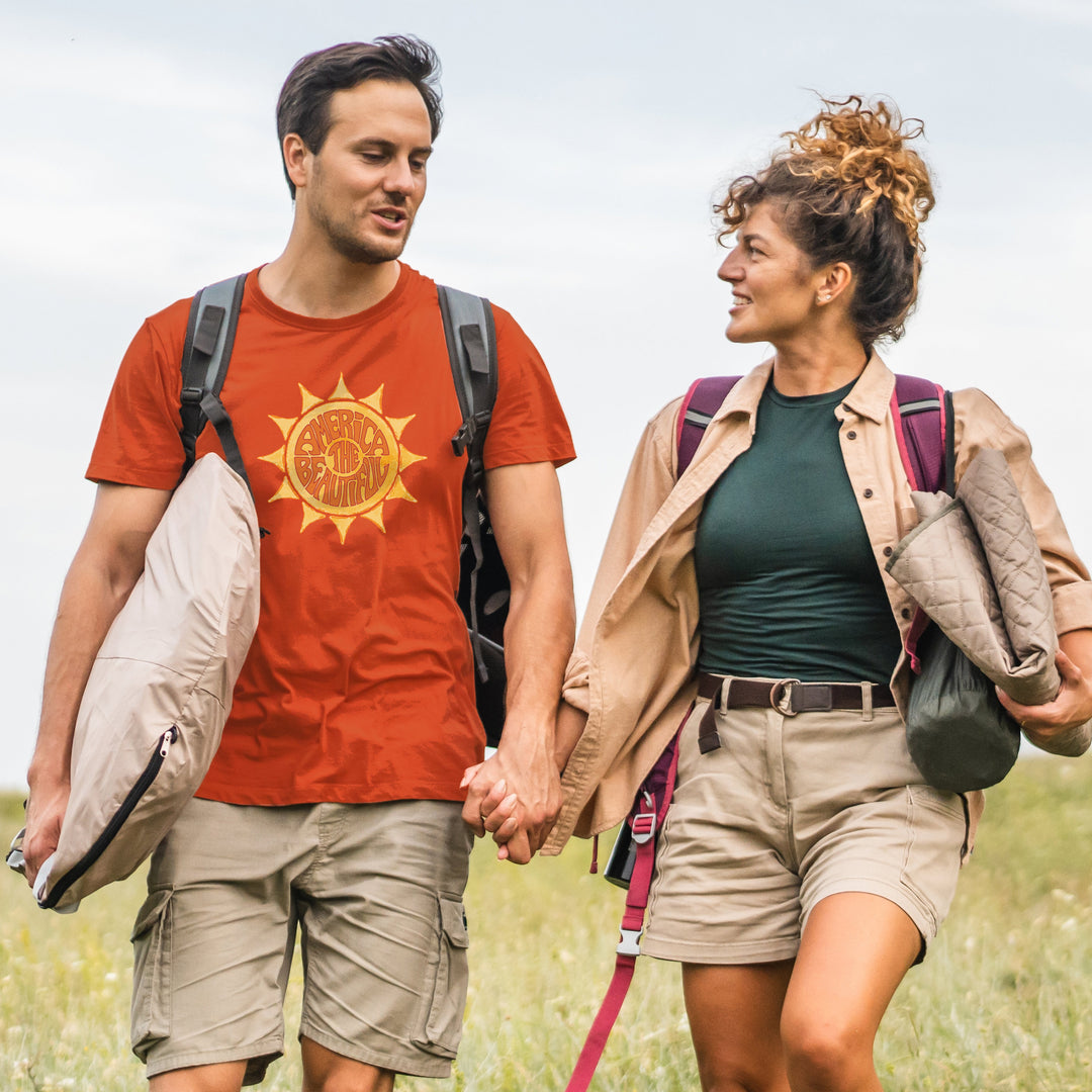 A couple walking in nature with the man wearing an America The Beautiful "awesome Sun" orange shirt