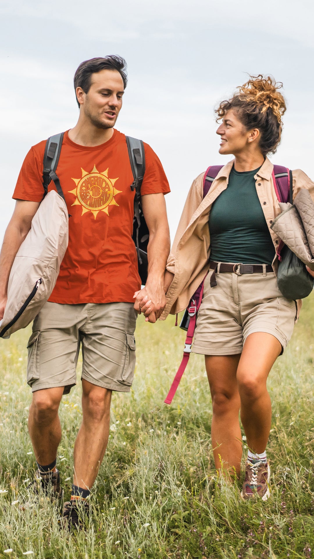 A couple walking in nature with the man wearing an America The Beautiful "awesome Sun" orange shirt