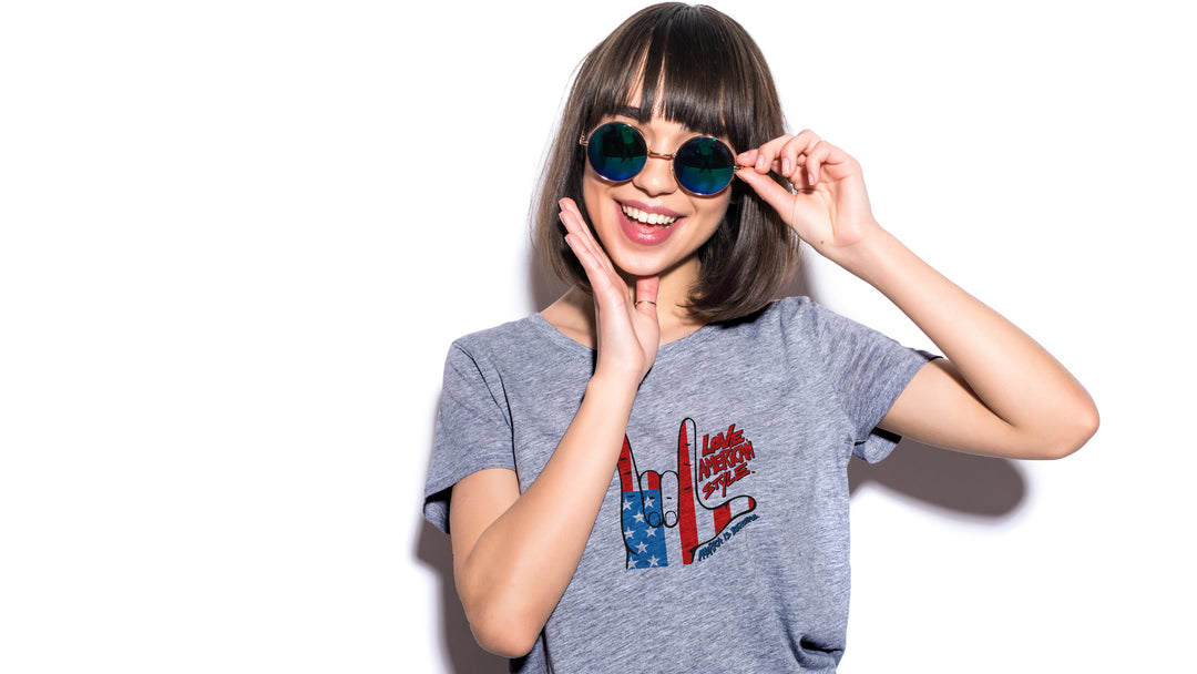 Woman wearing a Gray t-shirt with a graphic design of hands making a "I love you" shape and text