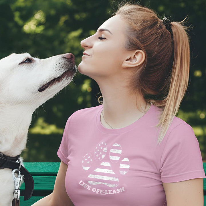 Woman in pink t-shirt with dog paw print on green bench with pet