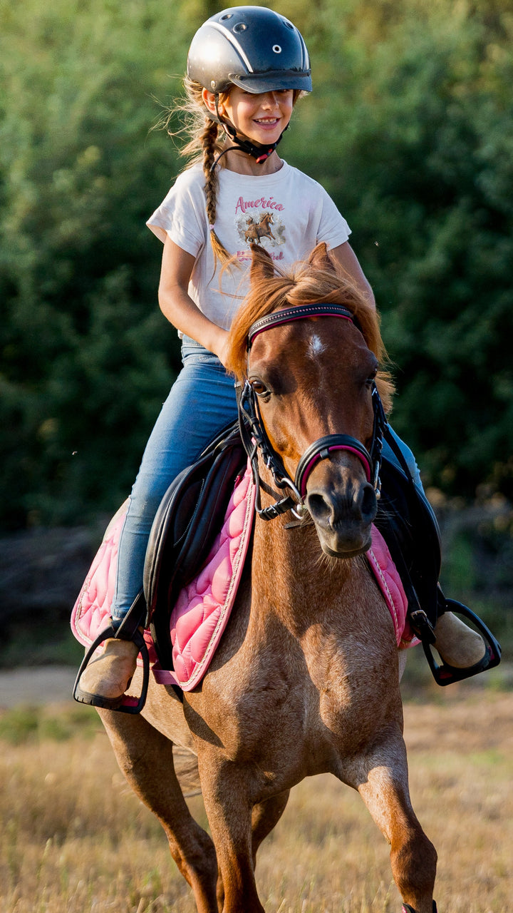 Girl riding horse wearing White t-shirt with horse graphic and &