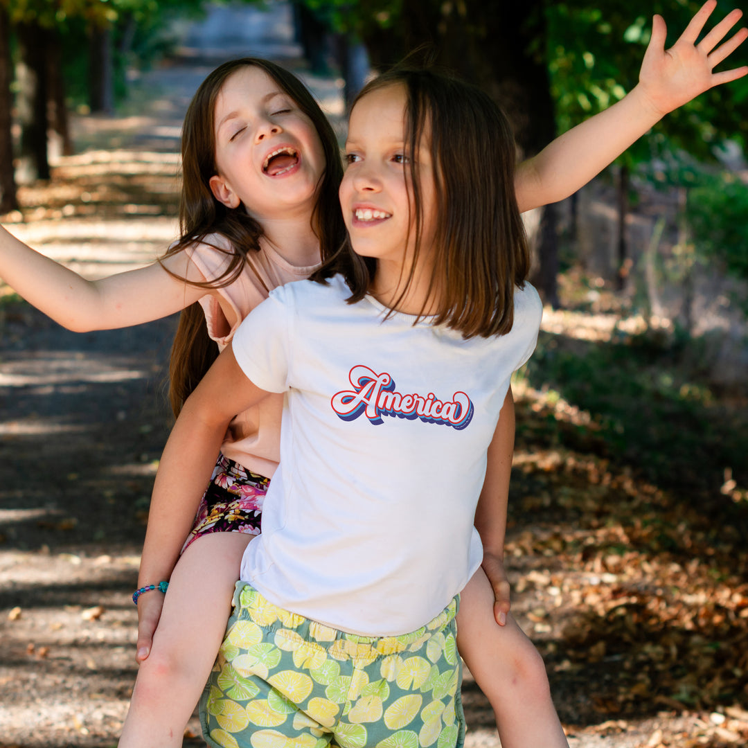 Two young girls playing outdoors with one wearing a &