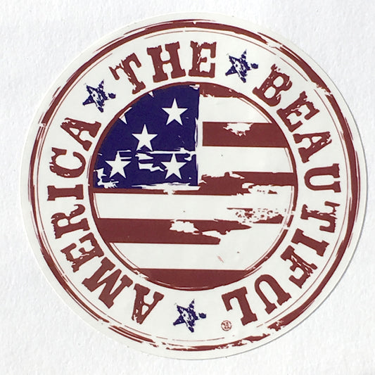 A round bumper sticker showing a weathered American Flag art with the words “AMERICA THE BEAUTIFUL” running around its perimeter with the words separated by three blue stars for a cool red white and blue look.