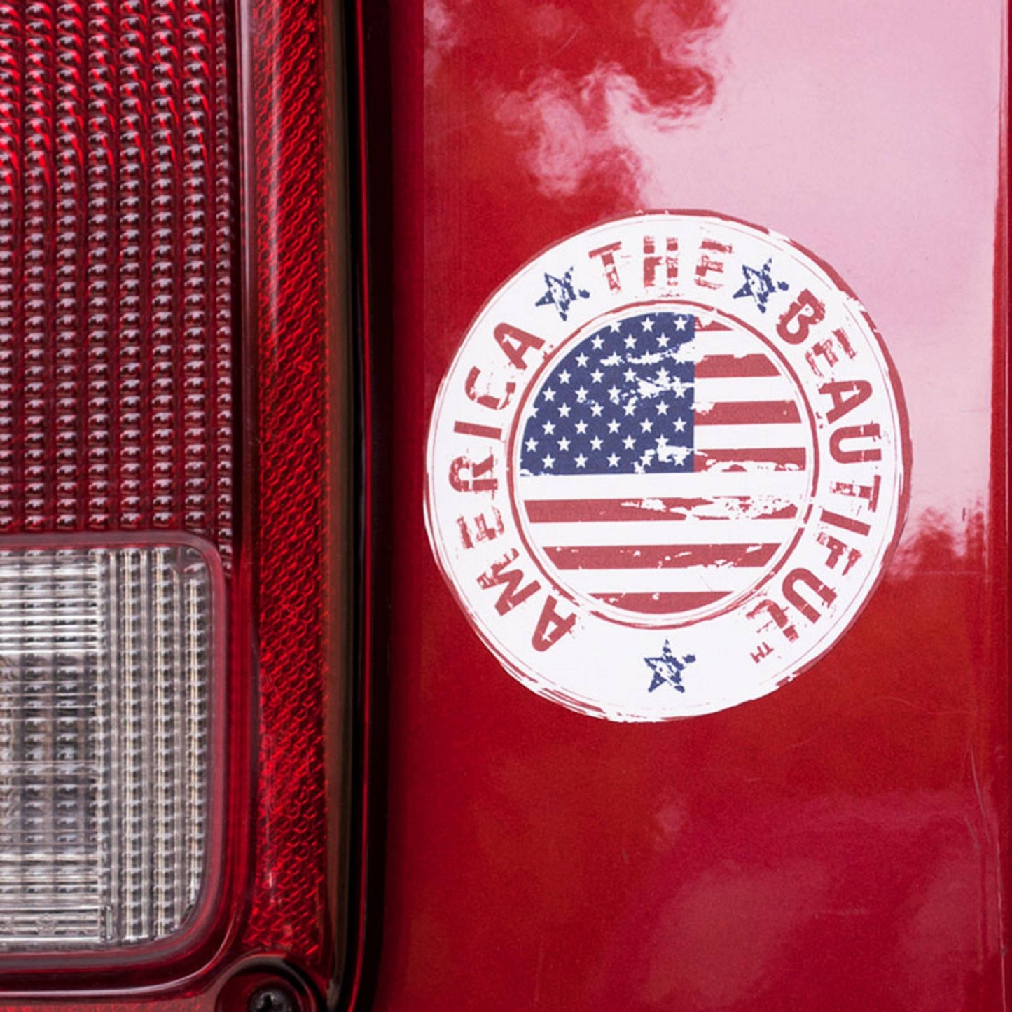 View of an America The Beautiful® Weathered American Flag Bumper Sticker on a car window.